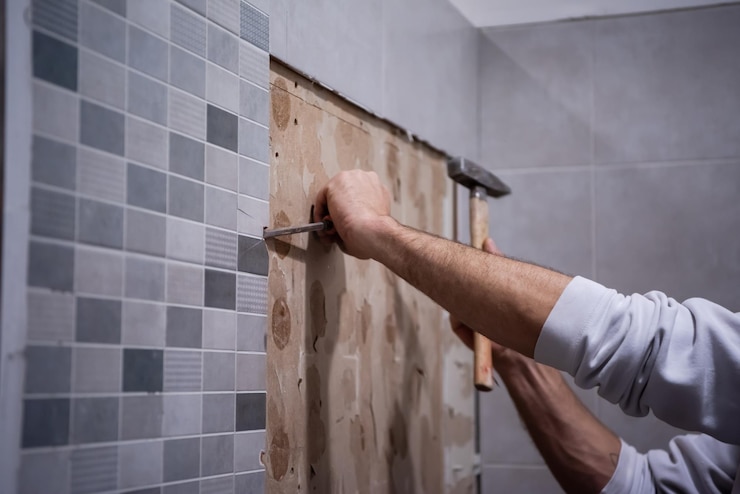 Foto trabalhador profissional remove azulejos antigos em um banheiro com martelo e cinzel