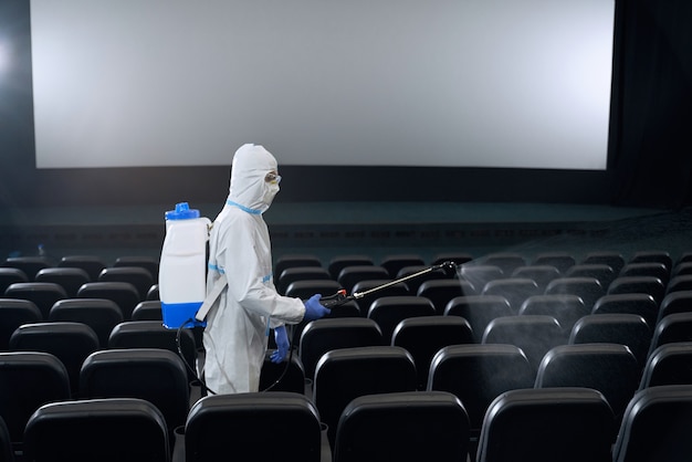 Trabalhador que faz a desinfecção com equipamento especial no cinema.