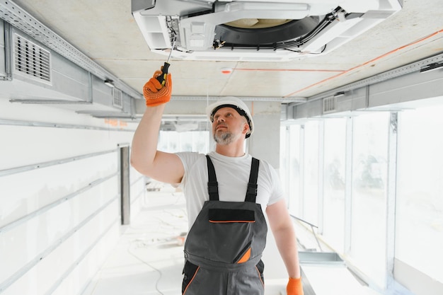 Foto trabalhador reparando unidade de ar condicionado de teto