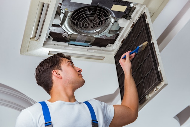 Foto trabalhador reparando unidade de ar condicionado de teto