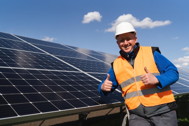 Trabalhador satisfeito mostrando os polegares para cima gesto enquanto está perto de painéis solares