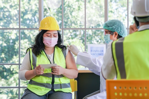 Trabalhador sentado para tomar vacina covid com enfermeira injetando vacina para obter imunidade