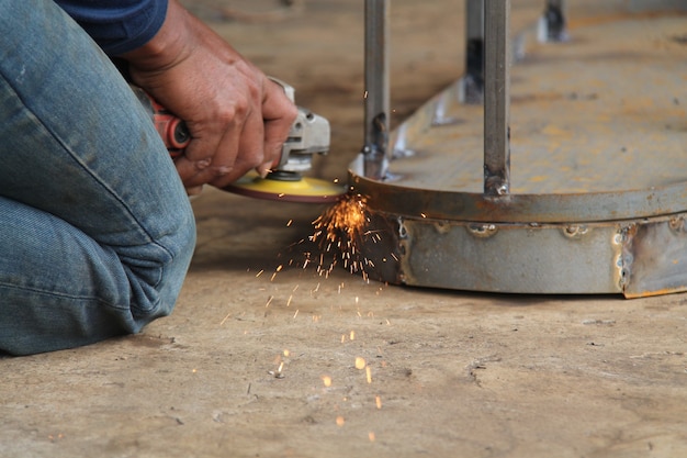 Foto trabalhador serrar metal com um moedor, faíscas voam