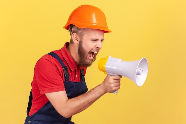 Trabalhador usando capacete protetor segurando megafone e gritando com expressão agressiva