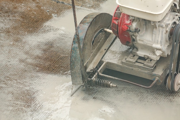 Trabalhador usando máquina de lâmina de serra de diamante cortando estrada de concreto no canteiro de obras