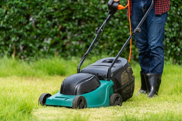 Trabalhador usando um cortador de grama cortando grama em casa