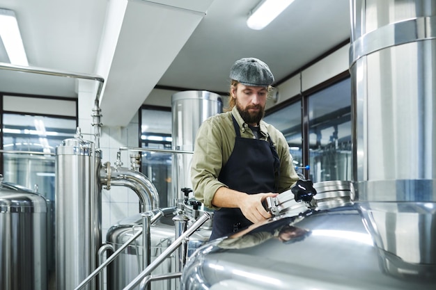 Trabalhador verificando cerveja fermentada