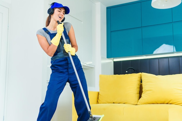 Trabalhadora atraente com fones de ouvido dançando com o swabber no meio do contemporâneo