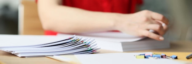 Trabalhadora de escritório com blusa vermelha procura documentos mulher trabalha com papéis prendendo folhas