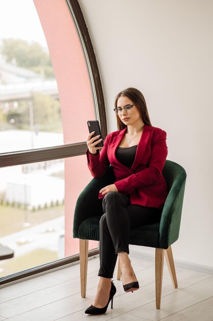 Trabalhadora de escritório ou secretária bem vestida usando celular dentro da sala de escritório