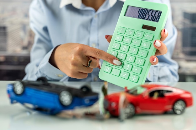 Trabalhadora de escritório sentada em uma mesa com uma simulação de um acidente de dois carros