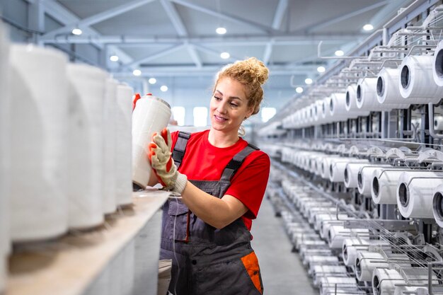 Trabalhadora de uma fábrica têxtil com bobinas de fio e máquina de costura industrial ao fundo