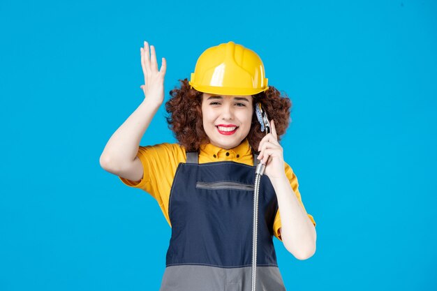 Trabalhadora de uniforme amarelo segurando o chuveiro no azul