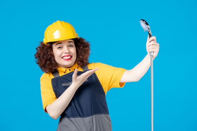 Trabalhadora de uniforme amarelo segurando o chuveiro no azul