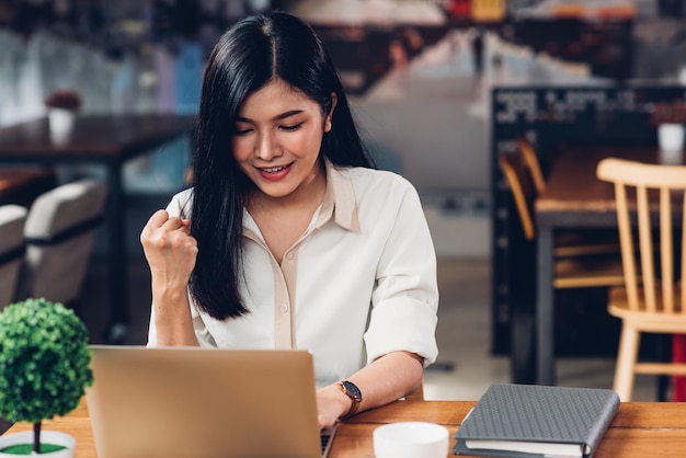 Trabalhadora freelancer com laptop, ele obtém os resultados com prazer na cafeteria