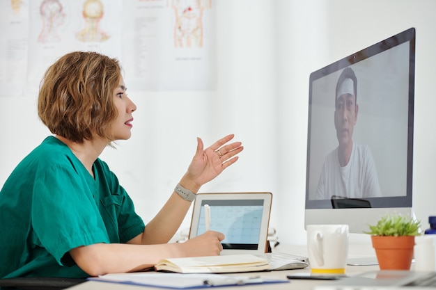 Trabalhadora médica falando com um paciente doente e anotando suas queixas