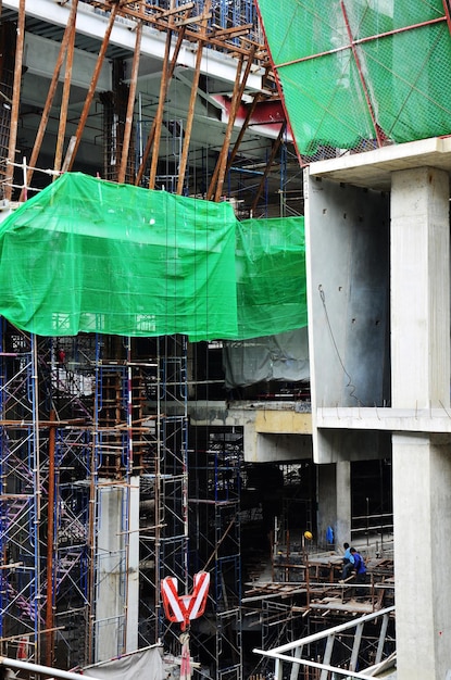 Trabalhadores asiáticos e trabalhadores tailandeses usam máquinas e máquinas pesadas, construtor de nova estrutura, edifício alto em andaime no canteiro de obras na capital em Bangkok, Tailândia