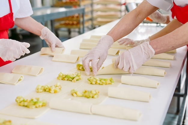 Trabalhadores da confeitaria preparam sobremesas com recheio