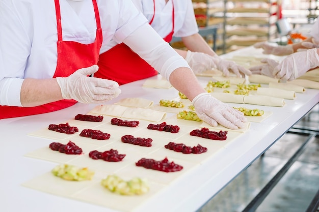 Trabalhadores da confeitaria preparam sobremesas com recheio