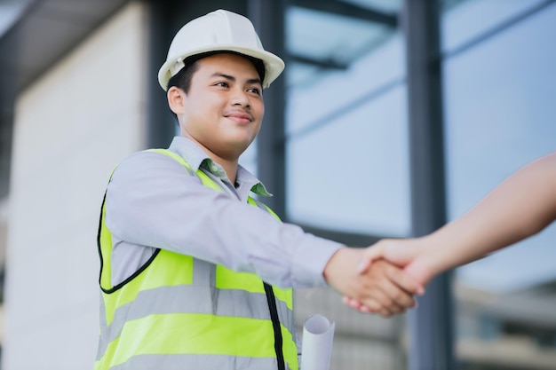 Trabalhadores da construção civil, apertando as mãos enquanto trabalham em equipe e conceito de cooperação após o término do canteiro de obras Trabalhador da construção civil, conceito de colaboração de sucesso