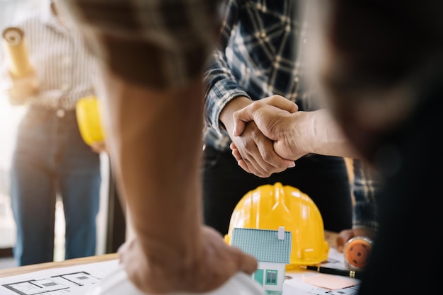 Trabalhadores da construção civil, arquitetos e engenheiros apertam as mãos enquanto trabalham para o trabalho em equipe e a cooperação depois de concluir um acordo em um conceito de cooperação bem-sucedida em uma instalação de escritório