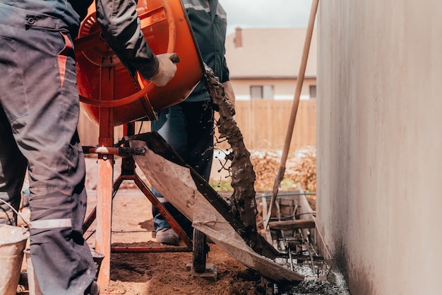 Trabalhadores da construção civil despejam concreto com um misturador de concreto.