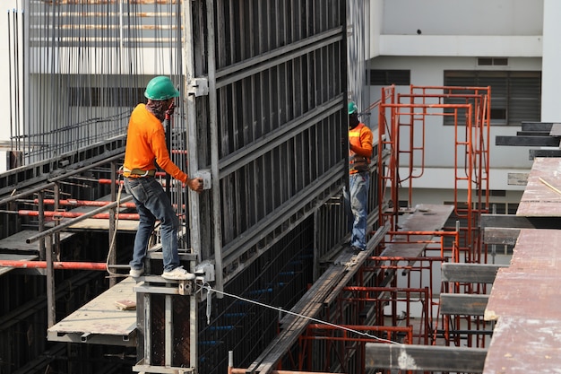 Trabalhadores da construção civil estão trabalhando em prédios altos para construir prédios.