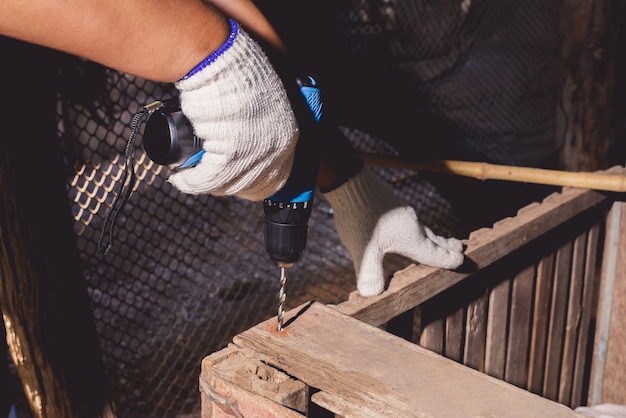 Trabalhadores da construção civil na camisa azul com luvas de proteção e trabalhando com furadeira