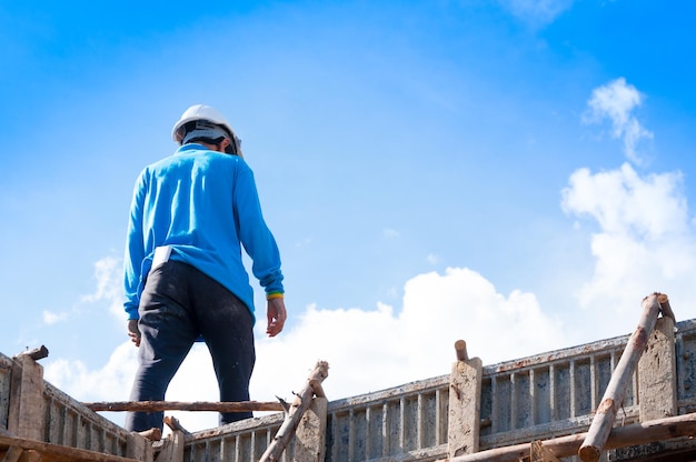 Trabalhadores da construção civil na construção, homem trabalhando em altura com céu azul no canteiro de obras