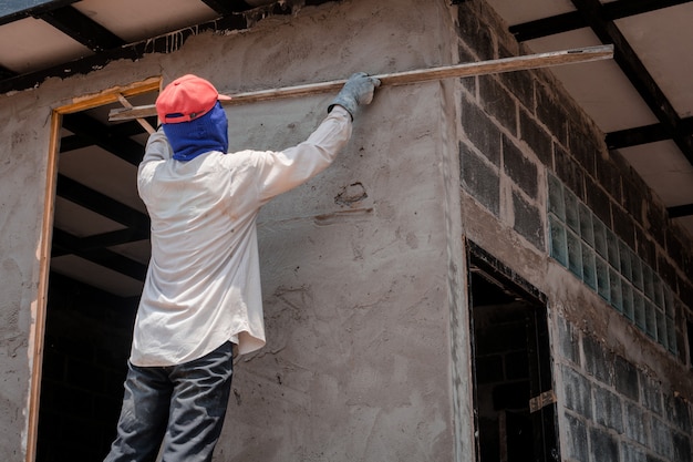 Trabalhadores da construção civil reboco parede do edifício usando cimento gesso