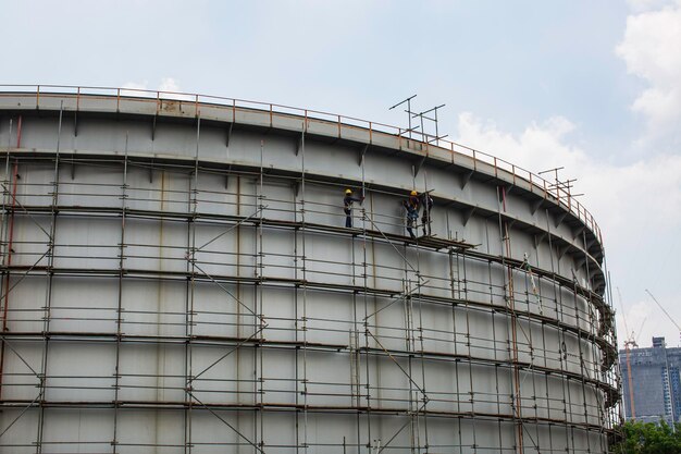 Trabalhadores da construção civil tanque de óleo instalando andaimes na refinaria do local