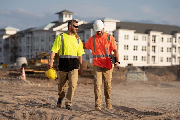 Trabalhadores da construção civil trabalhando no canteiro de obras Homens vestindo coletes de segurança e capacetes de construção Capataz de construção e construtor