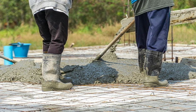 Trabalhadores da construção de concreto derramando estão despejando concreto entre os pisos de concreto comercial de um prédio em construção