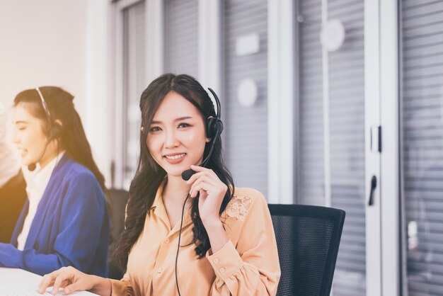 Trabalhadores da equipe asiática do call center juntos no escritório, Operadora de mulher sorridente de funcionários trabalhando com fone de ouvido