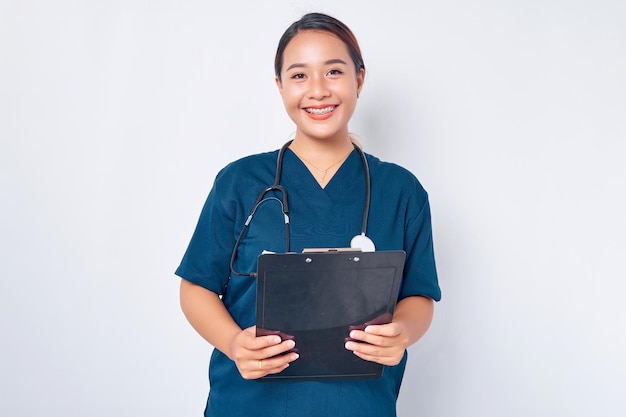 Trabalhadores da saúde sorrindo jovem enfermeira asiática vestindo uniforme azul com um estetoscópio segurando a prancheta isolada no fundo branco Conceito de medicina de saúde