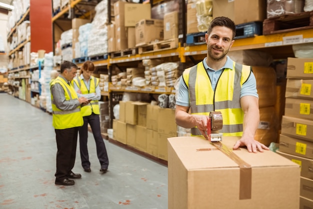 Trabalhadores de armazém sorridentes que preparam uma remessa