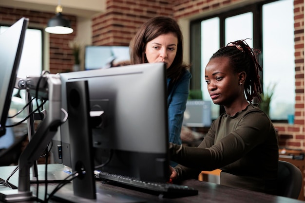 Trabalhadores de escritório da empresa criativa sentados à mesa no espaço de trabalho do escritório enquanto discutem sobre o desenvolvimento de gráficos. Desenvolvedores profissionais da agência fazendo brainstorming de ideias de design digital para usar no projeto.