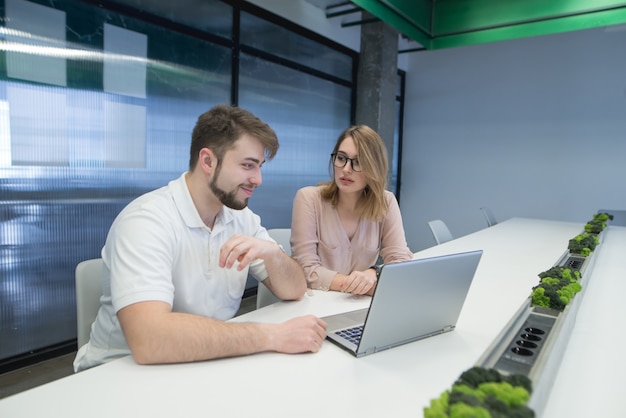 Trabalhadores de escritório, sentado em uma mesa perto de um laptop e falando.