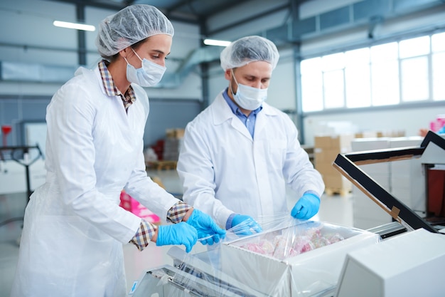 Trabalhadores de fábrica de confeitaria, caixa de embrulho em filme de embalagem