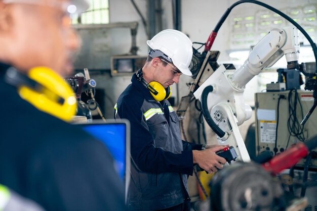 Trabalhadores de fábrica trabalhando com braço robótico adepto em uma oficina