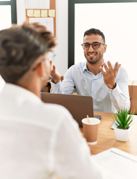 Trabalhadores de negócios de dois homens hispânicos sorrindo confiantes trabalhando no escritório