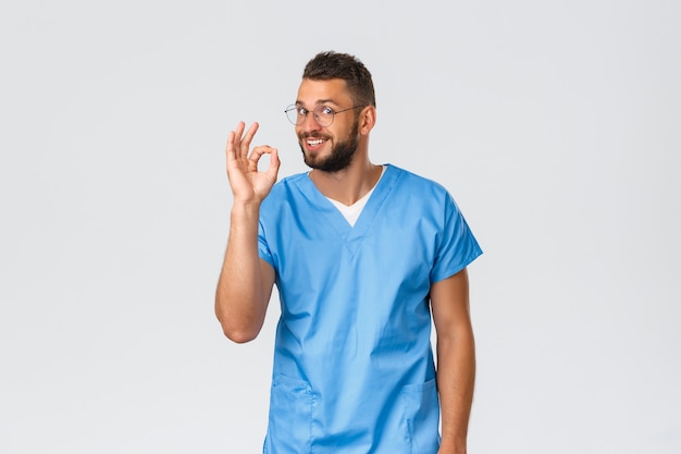 Trabalhadores de saúde, medicina, covid-19 e conceito de auto-quarentena pandêmica. O doutor tem a solução perfeita. Enfermeira amigável e sorridente de uniforme e óculos, mostrar tudo bem, tudo bem ou nenhum sinal de problema