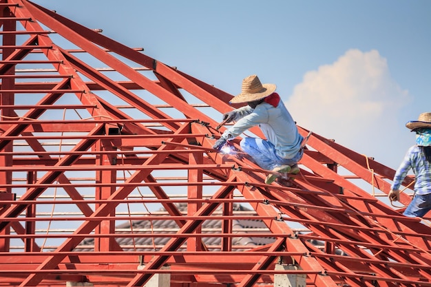 Trabalhadores de solda de construção instalando estrutura de armação de aço do telhado da casa