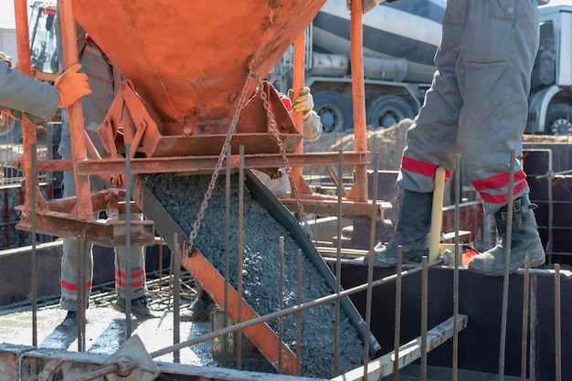 Trabalhadores despejam concreto na fundação em um canteiro de obras concretagem da fundação durante a construção do edifício trabalhos de concreto