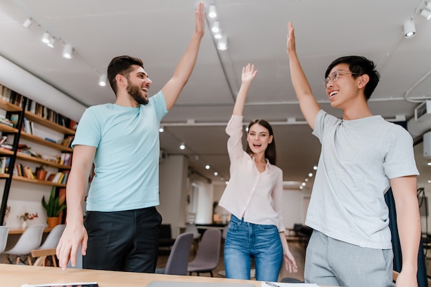 Trabalhadores diversos e felizes cooperando em equipe no escritório