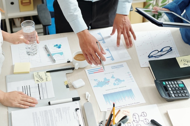 Trabalhadores do departamento de marketing se reunindo na mesa do escritório para analisar estatísticas financeiras e criar relatórios antes do prazo