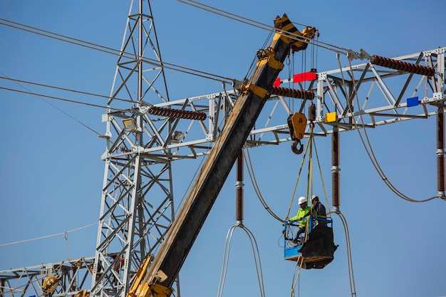 Trabalhadores do sexo masculino Instalação de postes de transmissão de energia elétrica de alta tensão no guindaste trabalho em risco de altura