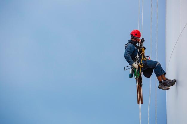 Trabalhadores do sexo masculino para baixo inspeção de acesso por corda de tanque de altura de trabalho de segurança de gás propano de gás propano de tanque de armazenamento de placa de concha de espessura em altura.