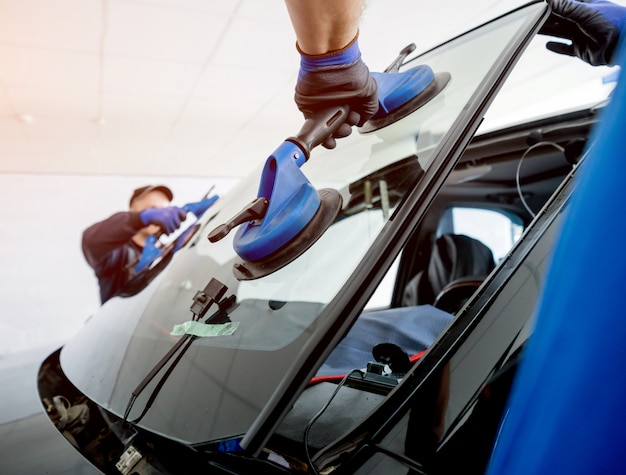 Foto trabalhadores especiais de automóveis substituindo pára-brisas ou pára-brisas de um carro na garagem da estação de serviço automóvel.