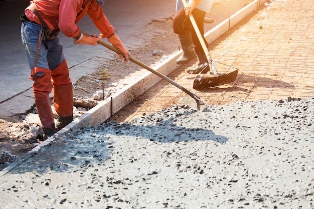Trabalhadores estão usando ferramentas para alisar o piso de concreto